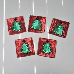 May include: Five red felt coasters with green sequined Christmas trees. The coasters are square and have a festive design.