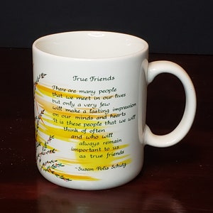 Pode incluir: Caneca de cerâmica branca com um design de aquarela amarelo e laranja. A caneca apresenta um poema sobre verdadeiros amigos, terminando com a citação "Susan Polis Schutz".