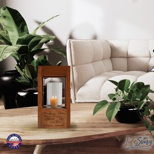 May include: A wooden candle holder with a glass cylinder for a candle. The holder has an engraved message that reads "In Loving Memory of Those who are FOREVER in our Hearts".