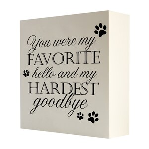 May include: A white wooden block with black text that reads "You were my FAVORITE hello and my HARDEST goodbye" with paw prints on the top and bottom.