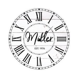 May include: White wooden clock with black Roman numeral hour markers and black hands. The clock face has a whitewashed woodgrain design and the text "Miller EST. 1976".