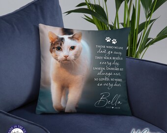 May include: A white and brown cat with green eyes is featured on a dark blue throw pillow. The pillow has a white text overlay that reads "Those who we love don't go away. They walk beside us every day. Unseen. Unheard. But always near. So loved. So missed. So very dear." The text "Bella 2017-2021" is also on the pillow.