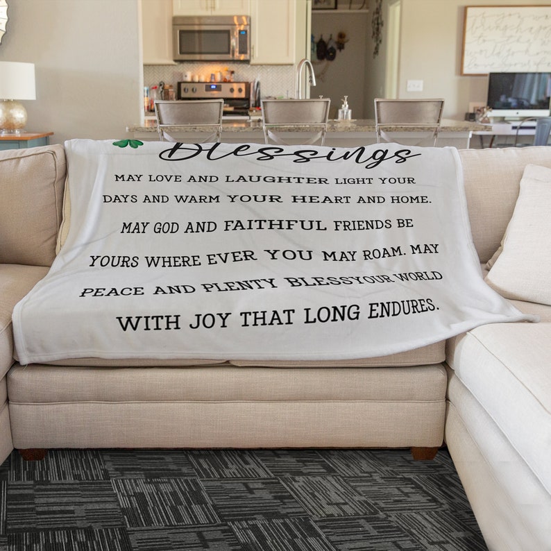 May include: White throw blanket with a black inscription that reads "Blessings May love and laughter light your days and warm your heart and home. May God and faithful friends be yours where ever you may roam. May peace and plenty bless your world with joy that long endures."
