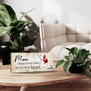 Puede incluir: Un letrero de madera con fondo blanco y un cardenal rojo posado en una rama con flores rosas. El letrero dice "Mamá, siempre en mi mente, para siempre en mi corazón."
