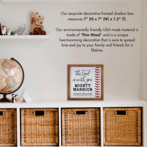 May include: A framed wood sign with a baseball stitch design and the text "The Lord is with you MIGHTY WARRIOR" with a name and date below. The sign measures 7 inches by 7 inches and is 1.5 inches thick.
