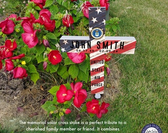 May include: A wooden cross stake with an American flag design. The cross is decorated with the words "JOHN SMITH", "UNITED STATE AIR FORCE", and the dates "04.17.49" and "02.09.24".