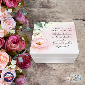 Puede incluir: Una caja cuadrada blanca con un diseño floral y el texto "ABUELA Y NIETA El amor entre una abuela y su nieta es para siempre." La caja está decorada con rosas rosas y hojas verdes.