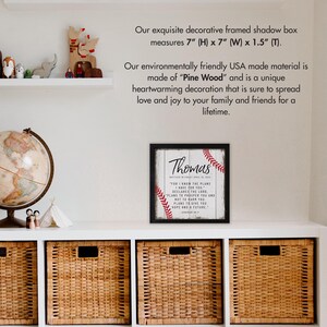 May include: A framed shadow box with a white background and red baseball stitching around the edges. The box has a black frame and a white woodgrain background. The text inside the box reads "Thomas" and a bible verse from Jeremiah 29:11. The box measures 7 inches high by 7 inches wide by 1.5 inches deep.