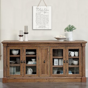 May include: A white wooden sign with black text that reads "The Broken Chain" and a poem about the loss of a loved one. The sign is hanging on a wall above a wooden cabinet with glass doors.