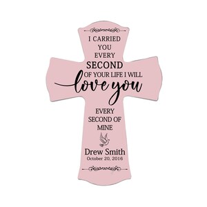 May include: A light pink wooden cross with the text "I carried you every second of your life I will love you every second of mine." The cross includes the name "Drew Smith" and the date "October 20, 2016."