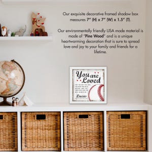 May include: A white framed shadow box with a baseball-themed print that reads "You are Loved" with a baseball graphic and the name "Lucas". The shadow box measures 7 inches high by 7 inches wide by 1.5 inches deep.