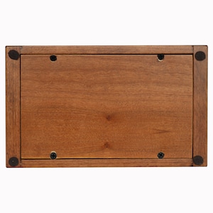 Puede incluir: La parte inferior de una caja de madera, te&ntilde;ida de marr&oacute;n. La caja tiene cuatro tornillos negros en la parte inferior.