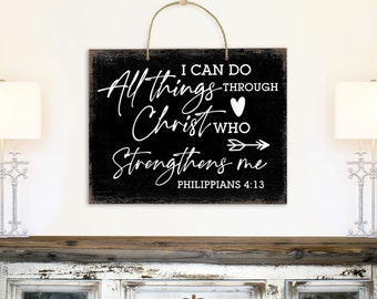 May include: Black wooden sign with white text that reads "I can do all things through Christ who strengthens me Philippians 4:13". The sign has a heart and arrow graphic.