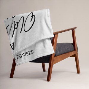 May include: White fleece throw blanket with black text that reads "Everything is going to be okay" and "Love endures."