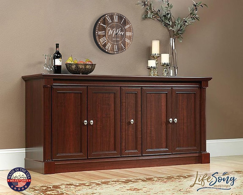 May include: A dark wood cabinet with six doors and silver door knobs. The cabinet is sitting on a wooden floor with a rug in front of it. A clock with the text "Miller" is hanging on the wall above the cabinet.
