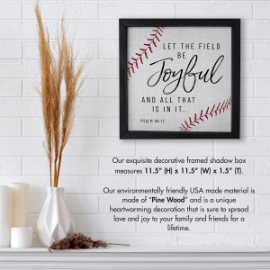 May include: A black framed shadow box with a white canvas background and red stitching in the shape of a baseball. The text "Let the field be Joyful and all that is in it. Psalm 96:12" is printed in black. The shadow box measures 11.5 inches high by 11.5 inches wide by 1.5 inches deep.