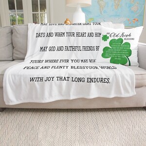 May include: White fleece throw blanket with black text that reads "May love and laughter light your days and warm your heart and home. May God and faithful friends be yours wherever you may roam. Peace and plenty bless your world with joy that long endures."  A green shamrock pillow with the text "An Old Irish Blessing" is on the couch behind the blanket.