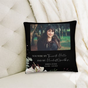 May include: Black throw pillow with a floral design and a photo of a woman. The text on the pillow reads "You were my favorite hello and my hardest goodbye. Sheryl Evans 9/12/1983 - 4/10/2021".