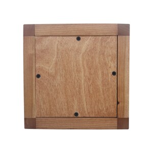 May include: A wooden frame with a light brown wood finish. The frame has a square shape and is made of solid wood. The frame has a smooth surface and is ready to be used for a picture or artwork.