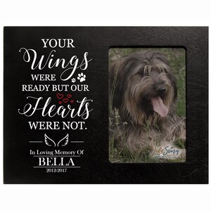 Puede incluir: Marco de fotos de madera negro con una inscripción blanca que dice "Your Wings Were Ready But Our Hearts Were Not. In Loving Memory Of Bella 2012-2017". El marco tiene una foto de un perro marrón y gris con la lengua fuera.