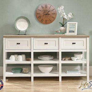 May include: White wooden shelf unit with three drawers and three shelves. The shelves are filled with white dishes and a wooden clock with the words "All our love and best wishes" and "Sofia" on the face.
