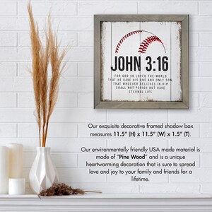 May include: A framed wood sign with a white background and a red baseball graphic. The sign features the text "JOHN 3:16" and a Bible verse about God's love for the world. The frame is gray and measures 11.5 inches high by 11.5 inches wide by 1.5 inches thick.