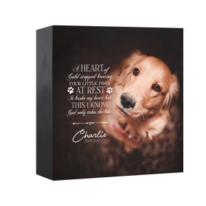 May include: A black rectangular memorial block featuring a golden retriever looking upward. The text reads: A HEART of Gold stopped beating, FOUR LITTLE PAWS AT REST It broke my heart but THIS I KNOW God only takes the best. Charlie 2015-2021.
