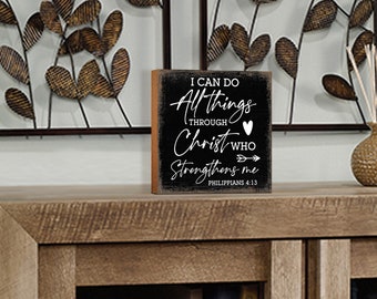 May include: Black wooden block sign with white text that reads "I can do all things through Christ who strengthens me - Philippians 4:13".