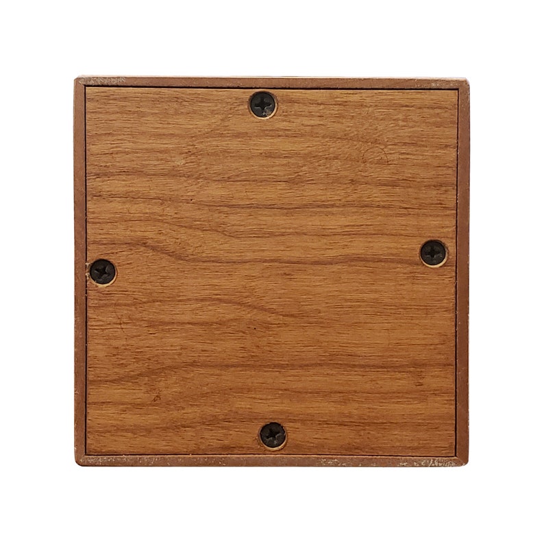 May include: A wooden square box with a brown woodgrain finish. The box has four screws on the front side.