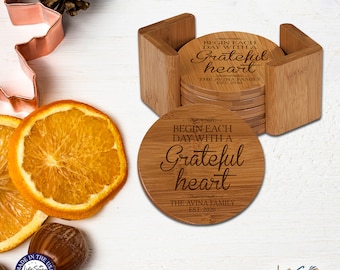 May include: Set of six round wooden coasters with a bamboo holder. Each coaster features the engraved text "Begin each day with a Grateful heart" and "The Avina Family Est. 2020".