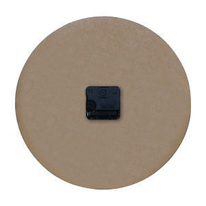 May include: The back of a round, brown clock with a black clock mechanism. The clock mechanism has the letters CE and the words "1288 Hz" printed on it.