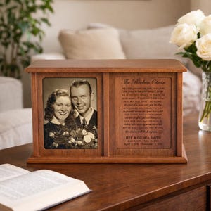 May include: A wooden memorial box with two sections. One side features a black and white photo of a couple, the other side has engraved text of a poem titled "The Broken Chain" and the names Jeff & Gloria Smith with dates.