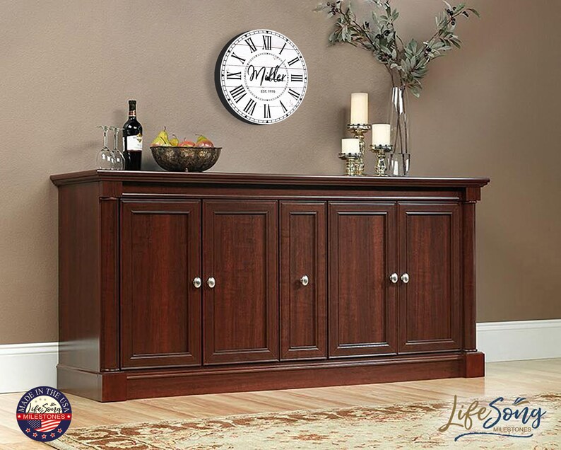 May include: A dark wood cabinet with six doors and silver door knobs. The cabinet is sitting on a wooden floor with a rug in front of it. There is a clock on the wall behind the cabinet with the name "Miller" on it.
