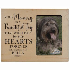 Puede incluir: Un marco de fotos de madera con una foto de un perro. El marco tiene el texto "YOUR Memory is a Beautiful Joy THAT WILL LIVE in our HEARTS FOREVER In Loving Memory Of BELLA 2012-2017" grabado en él.