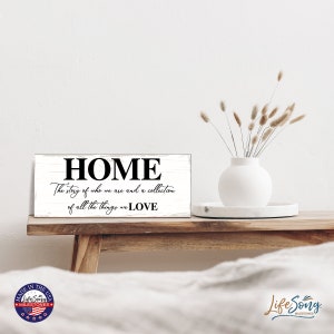May include: White wooden sign with black text that reads "HOME The story of who we are and a collection of all the things we LOVE".