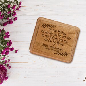 May include: A wooden engraved cutting board with the text "The Lord Bless You and Keep You. The Lord Make His Face Shine Upon You... And Give You Peace" and the name "Sofia Grace Smith" with the date "Dedicated on April 4, 2017".