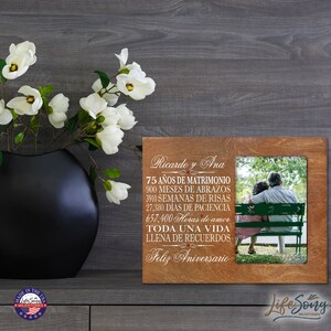 May include: A wooden photo frame with a brown background and a white inscription. The inscription reads "Ricardo y Ana 75 años de matrimonio 900 meses de abrazos 3910 semanas de risas 27,380 dias de paciencia 657,400 horas de amor Toda una vida llena de recuerdos Feliz Aniversario". The frame has a photo of an older couple sitting on a bench.