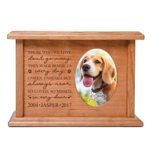 May include: Wooden pet urn with a photo of a dog and the inscription "Those who we love don't go away. They walk beside us every day. Unseen, unheard, but always near. So loved, so missed, so very dear. 2004-Jasper-2017"