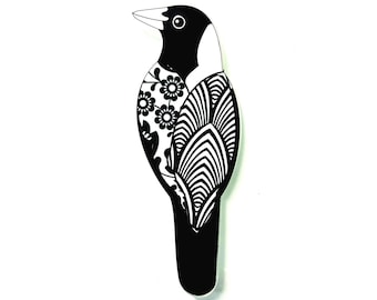 Pode incluir: Um pássaro decorativo em preto e branco com intrincados padrões florais e geométricos. A cabeça e a cauda do pássaro são pretas, enquanto o corpo apresenta desenhos detalhados. A obra de arte está sobre um fundo branco liso.