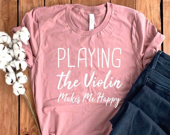 May include: A pink t-shirt with the text "PLAYING the Violin Makes Me Happy" in white lettering.