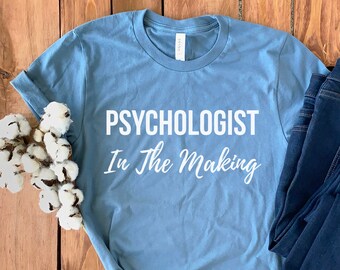 May include: A light blue t-shirt with the text "Psychologist In The Making" in white lettering.