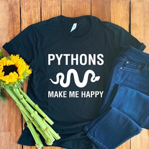 May include: Black t-shirt with white text that reads "Pythons make me happy" and a white snake graphic.