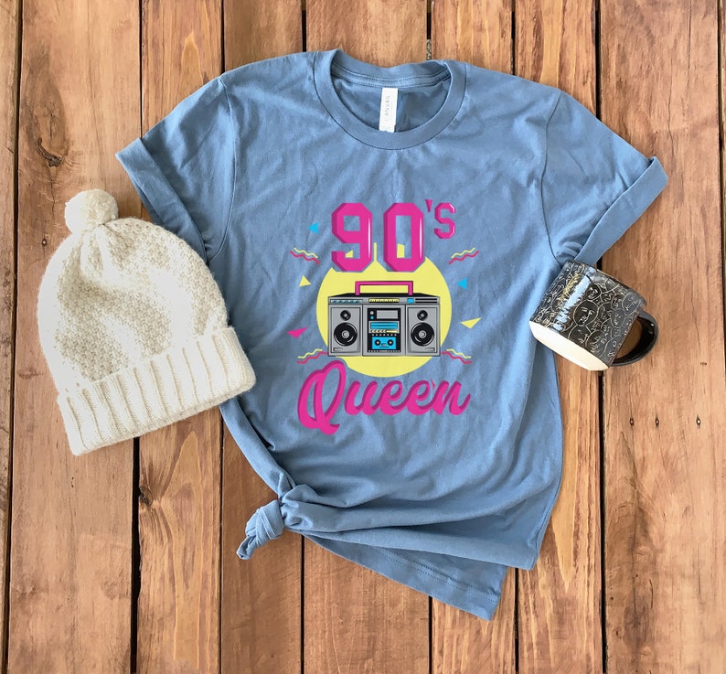 May include: A blue t-shirt with a pink and yellow graphic of a boombox and the text "90's Queen".