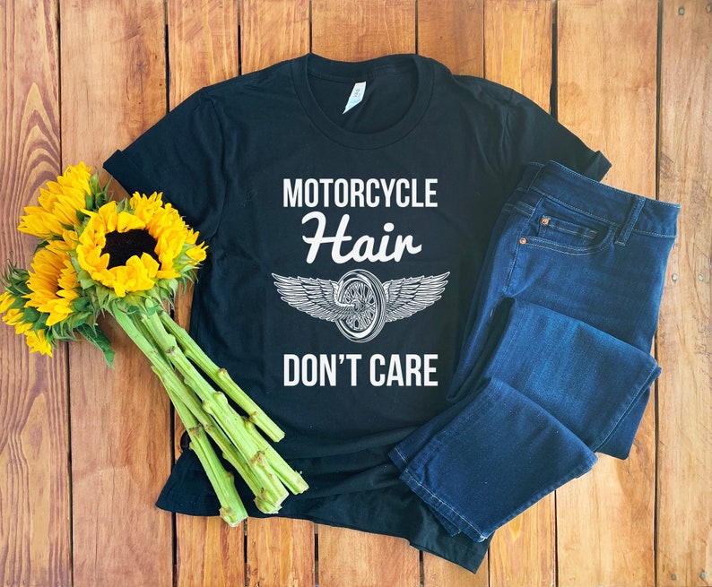 May include: Black t-shirt with white text that reads "Motorcycle Hair Don't Care" and a graphic of a motorcycle wheel with wings.