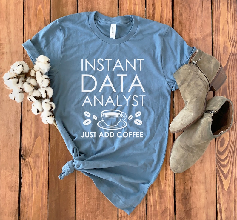 May include: A blue t-shirt with white text that reads "Instant Data Analyst Just Add Coffee". The text is accompanied by a graphic of a coffee cup and coffee beans.