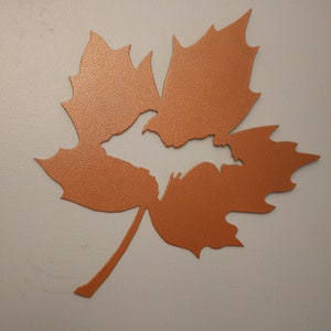 May include: A copper-colored metal maple leaf with a cut-out shape of the Upper Peninsula of Michigan.
