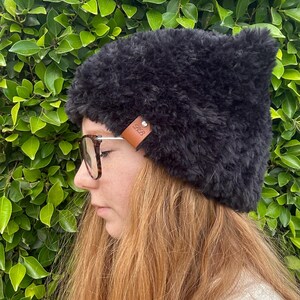 May include: A black fuzzy beanie with a brown leather patch that says "GRB" on it.