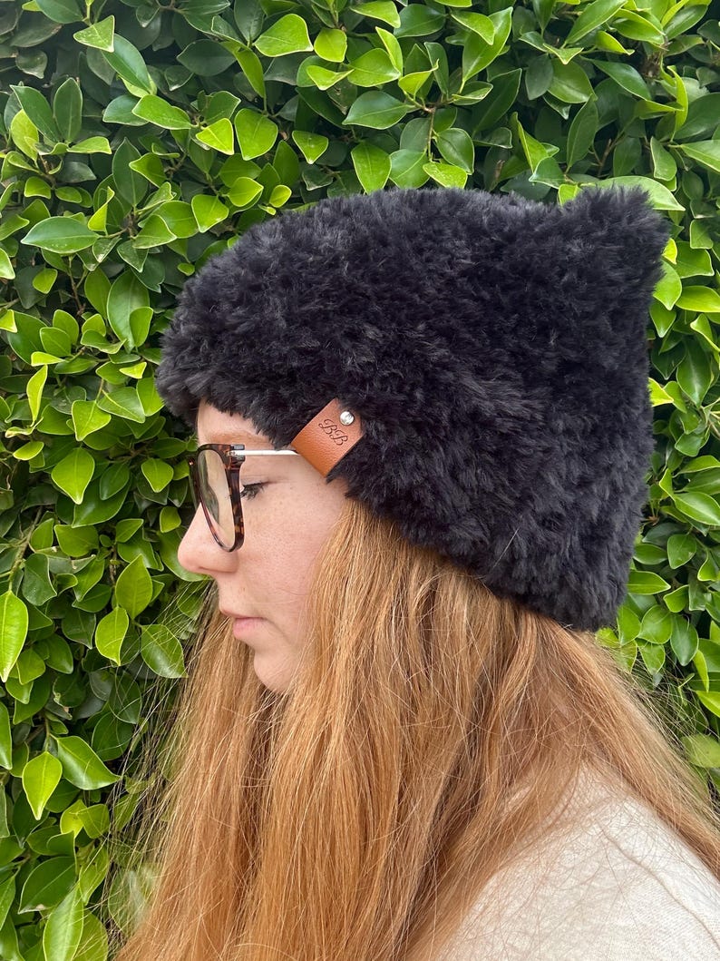 May include: A black fuzzy beanie with a brown leather patch that says "GRB" on it.