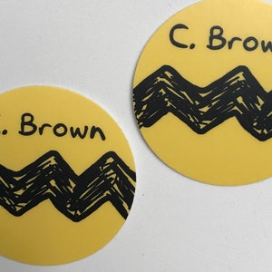 May include: Two yellow round stickers with black zig-zag patterns and the text "C. Brown" on each.
