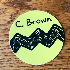 May include: A yellow circle sticker with a black zig-zag pattern and the text "C. Brown" in black.
